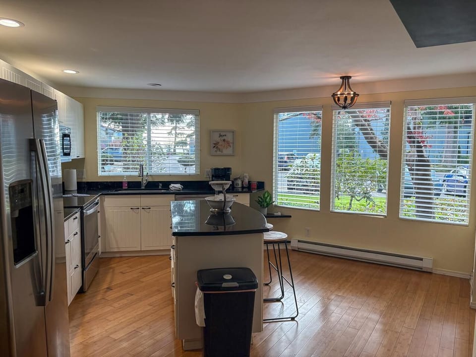 Black granite countertops top the kitchen island and perimeter, with white cabinetry and stainless steel appliances.