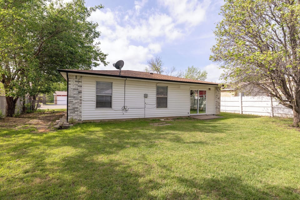 Fully fenced private backyard with lush green lawn and large mature shade tree.
