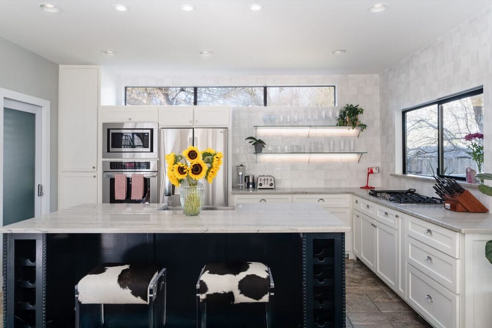 Stunning white marble kitchen with bar seating and elegant glassware accents.