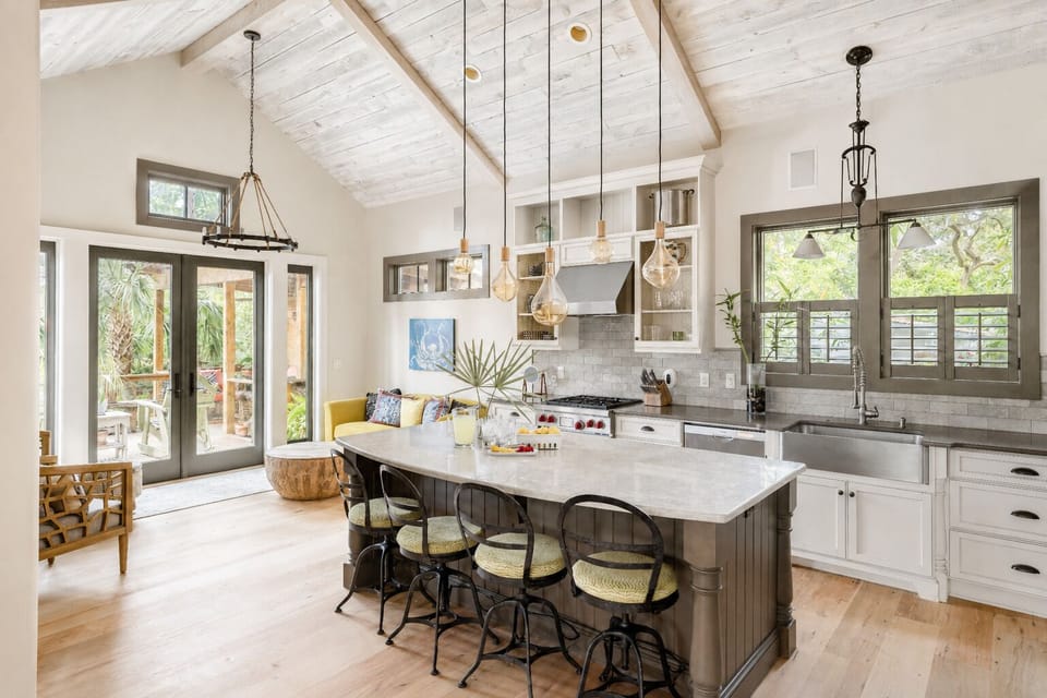 There is an open-concept living area and kitchen characterized by soaring 14-foot vaulted ceilings and washed reclaimed-wood beams