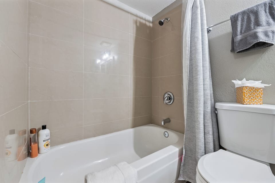 Clean bathroom with a relaxing bathtub and complete basic essentials provided fo