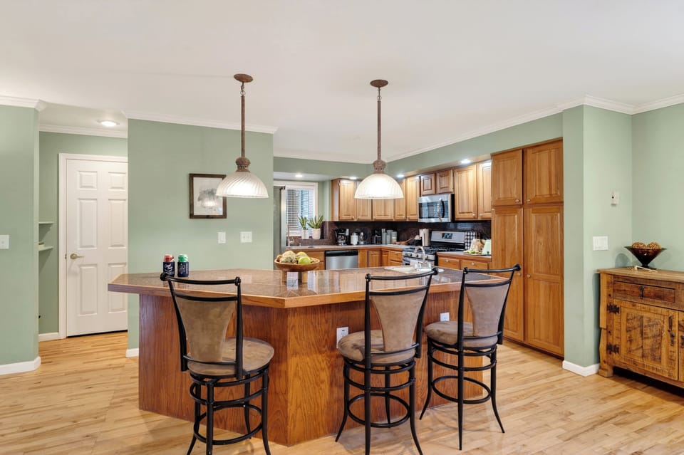 Breakfast bar with three high-top stools and pendant lighting.