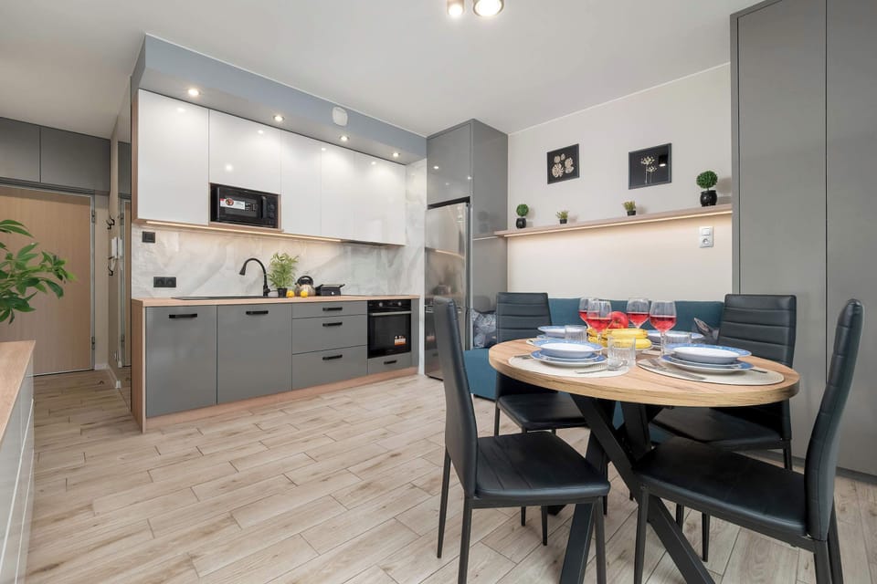 This wide-angle shot captures the open-plan layout connecting the kitchen and the dining area. The consistent use of grey, white, and wood tones creates a cohesive interior design.