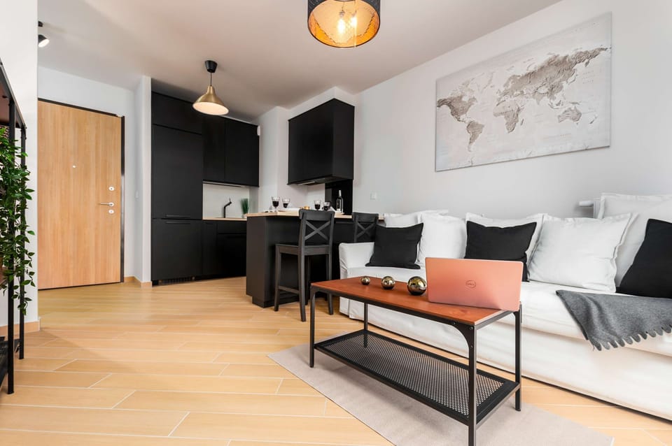 A wide-angle view of the living room shows the transition from the kitchenette to the living area. The light wood flooring ties the different functional zones together seamlessly.