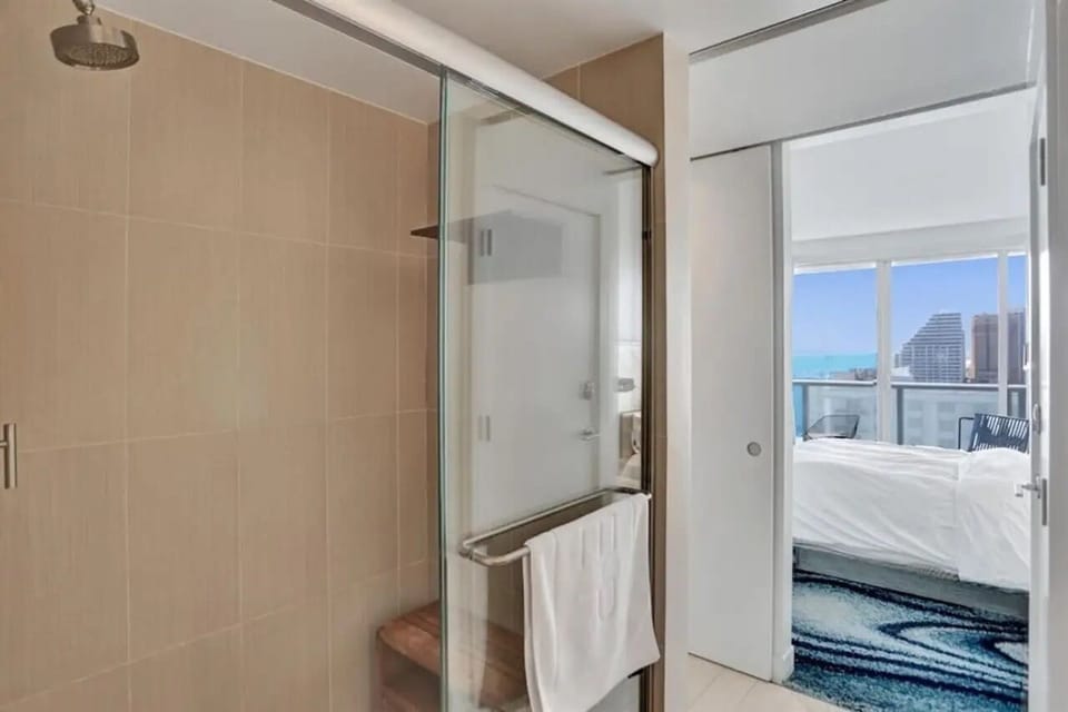 Modern bathroom with glass walk-in shower, fresh bath towels, and stocked essentials including shampoo, conditioner, and body wash for a comfortable stay at W Residences Fort Lauderdale Beach.