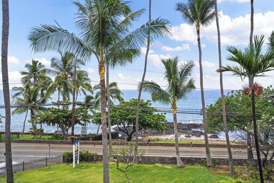 Tropical paradise awaits with swaying palm trees, lush greenery, and ocean views just across the street from this coastal Hawaiian retreat.