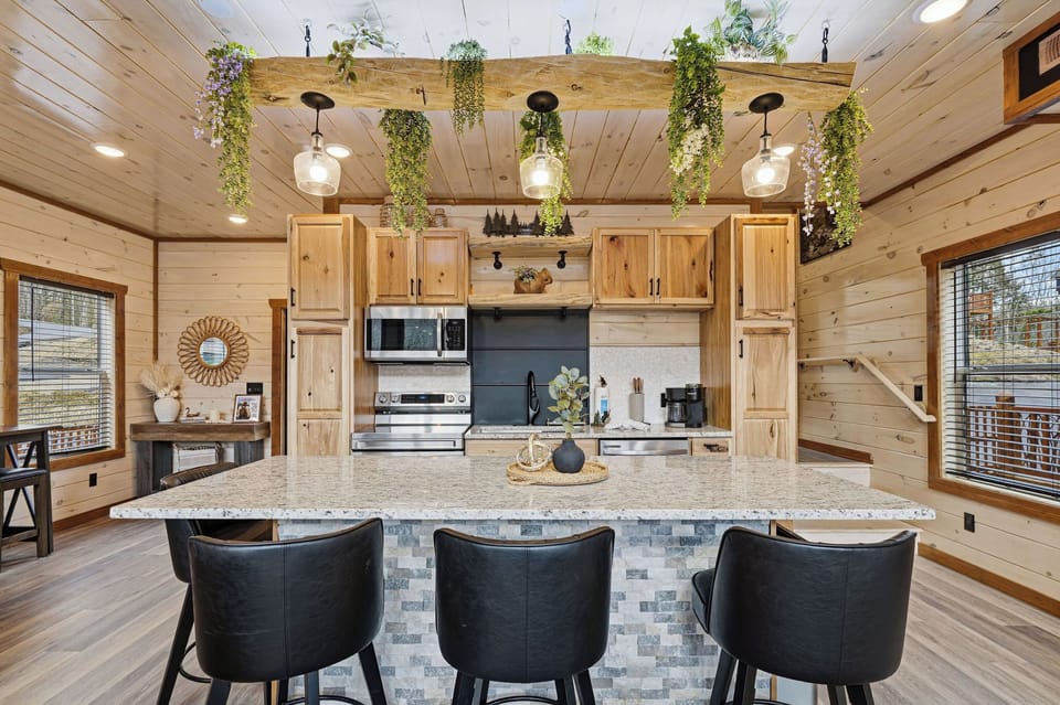 Step into your rustic-chic kitchen where modern appliances meet cozy cabin charm. Hanging plants and warm wood create the perfect cooking sanctuary.