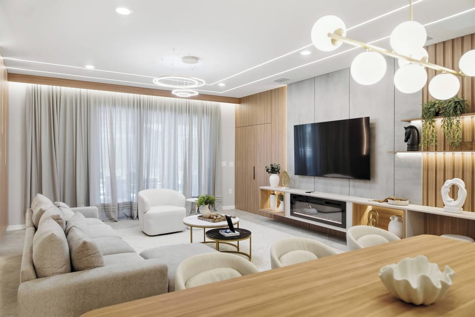 Unwind in a stylish living room with a cozy light-colored sofa and chic accent chairs. Soft, natural light through elegant drapes enhances modern decor, creating a warm and inviting space for your comfort.