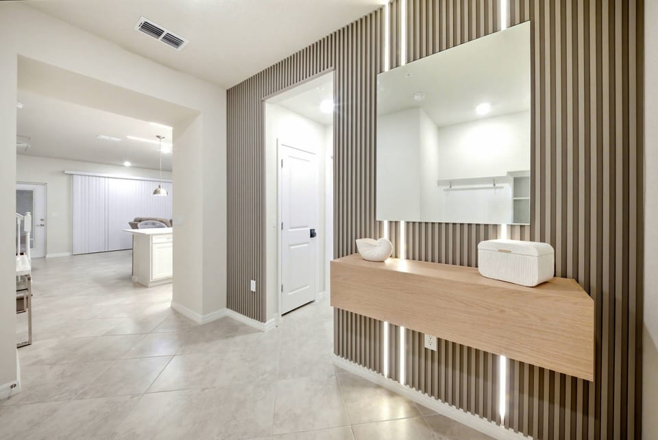 Welcome to a stylish entryway that blends function and design, featuring a sleek wooden console with integrated lighting, a large wall mirror for added depth, and a textured accent wall that brings a modern flair to your home.