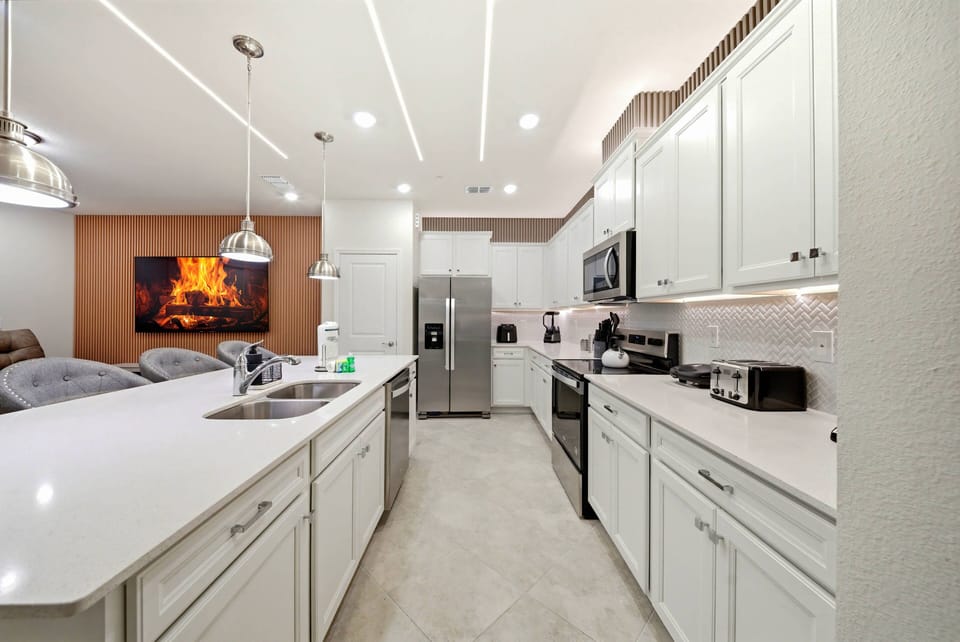 Welcome to this stylish kitchen, where sleek white cabinetry and modern appliances create a bright, functional space. The elegant quartz countertop offers ample room for meal prep, enhanced by soft, inviting lighting.