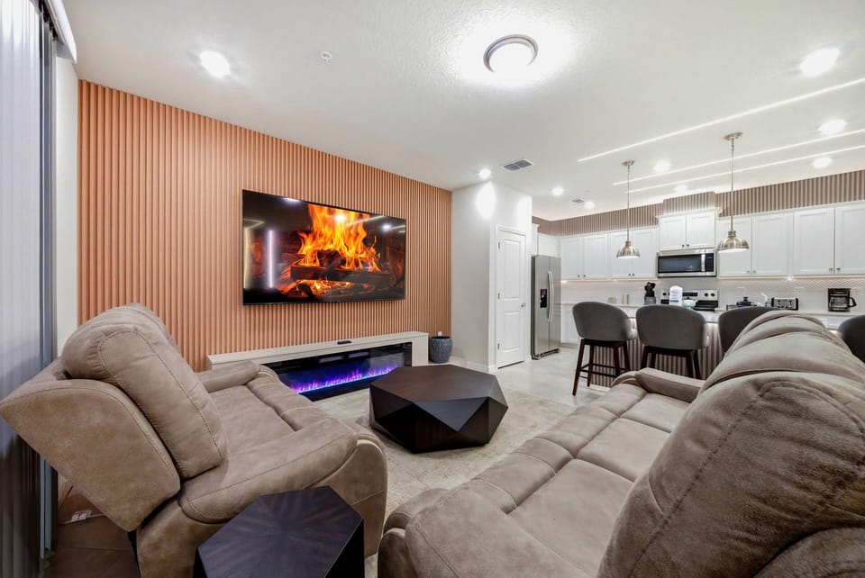 Unwind in the cozy living area with plush taupe sofas and a vibrant wall-mounted TV. The sleek coffee table adds a modern touch, and soft lighting creates a warm, inviting atmosphere for your relaxation.