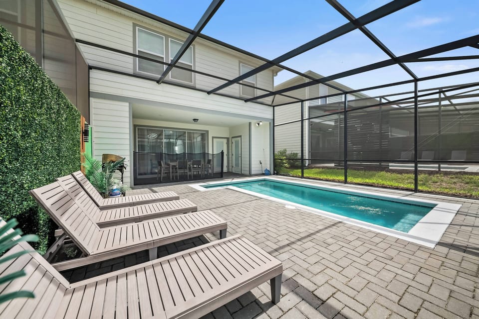 Bask in the sun beside your private pool, surrounded by sleek decking and lush greenery. The expansive screened enclosure allows for enjoyable outdoor living while ensuring a tranquil atmosphere for relaxation.