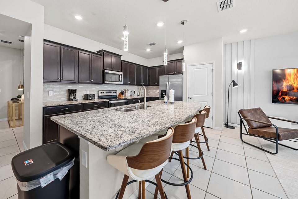 This stylish kitchen features dark cabinetry and stunning granite countertops, offering a beautiful contrast. Elegant barstools invite casual dining, and modern appliances ensure you have everything for your culinary adventures.