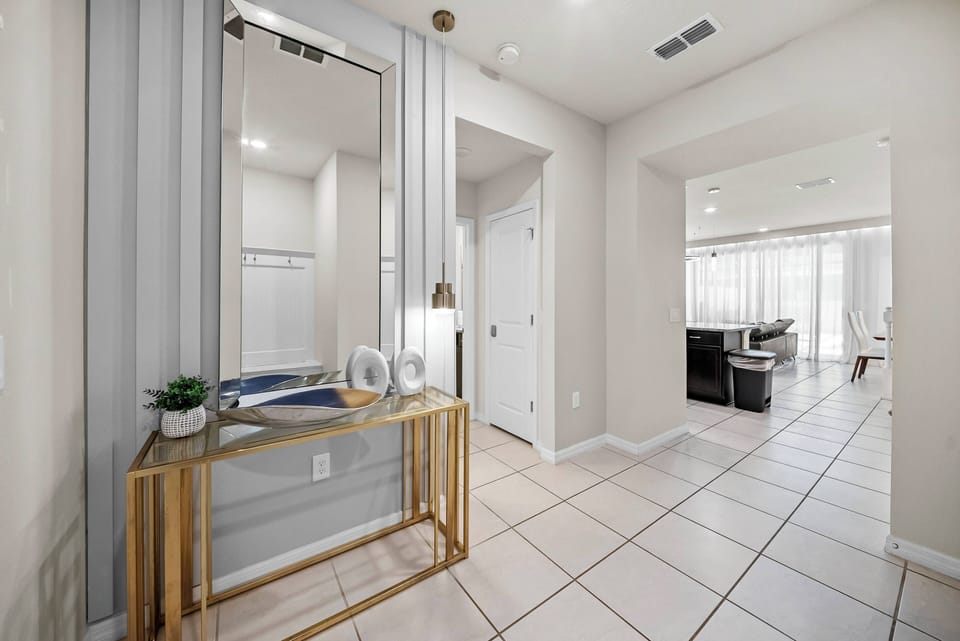 Welcome to this stylish entryway, where a sleek gold-accented console table and a large mirror enhance the bright, airy atmosphere. Elegant tile flooring and a soft color palette create a warm and inviting tone for your stay.