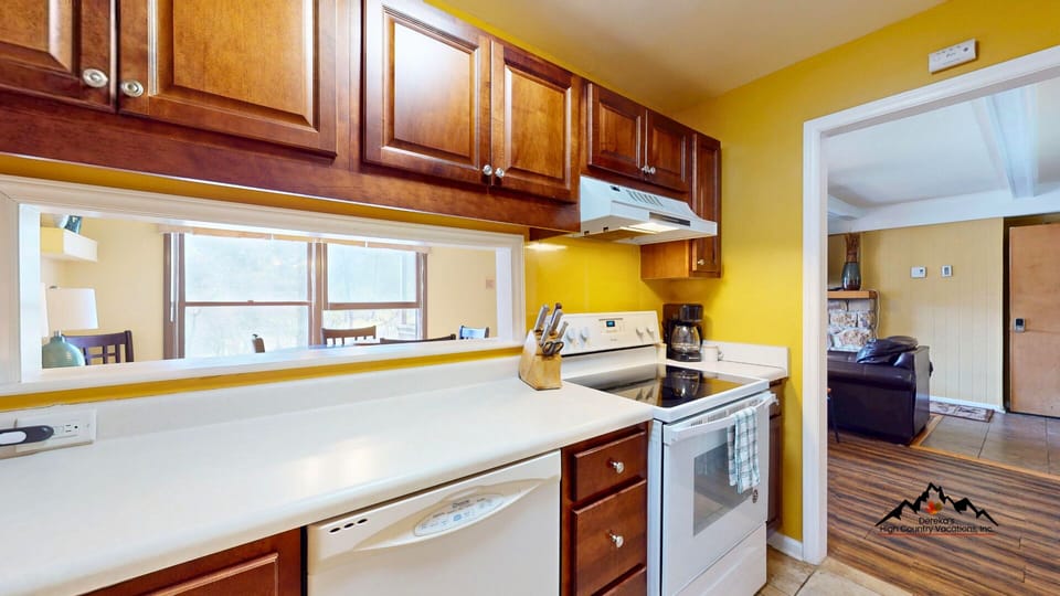 Your fully equipped kitchen awaits with rich wood cabinets, modern appliances, and sunny yellow walls that brighten your cooking adventures.