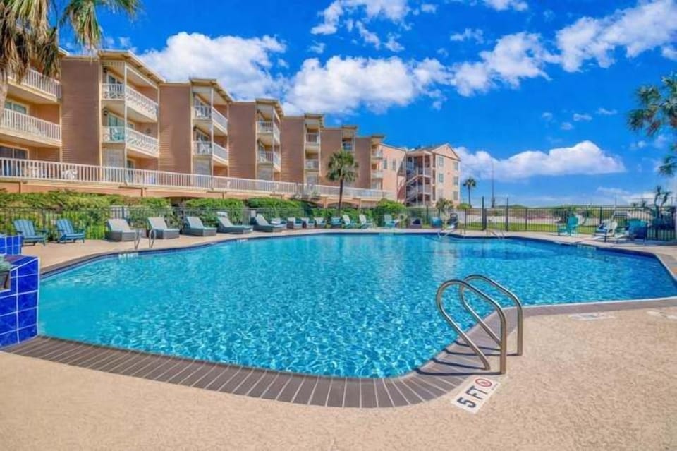 Resort-style pool with lounge seating and sunny balcony views