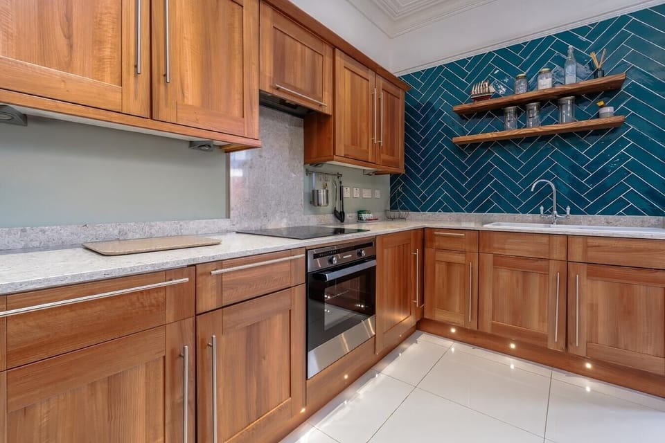- Kitchen with wooden cabinets oven stove and modern backsplash   - Open layout with shelves for glassware and bright lighting   - Functional design for cooking meals during your city stay  