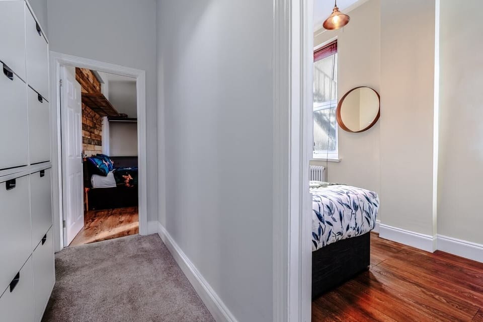 - Hallway view connecting bedrooms with carpet and wood flooring   - Clean white walls and open design brighten interior pathways   - Easy flow between rooms making layout functional and simple  