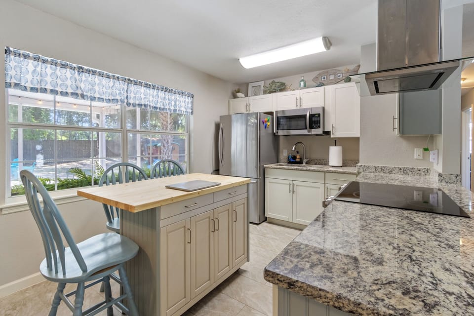 Prepare family meals in this fully equipped, coastal-themed kitchen, featuring modern stainless steel appliances and durable granite countertops.
