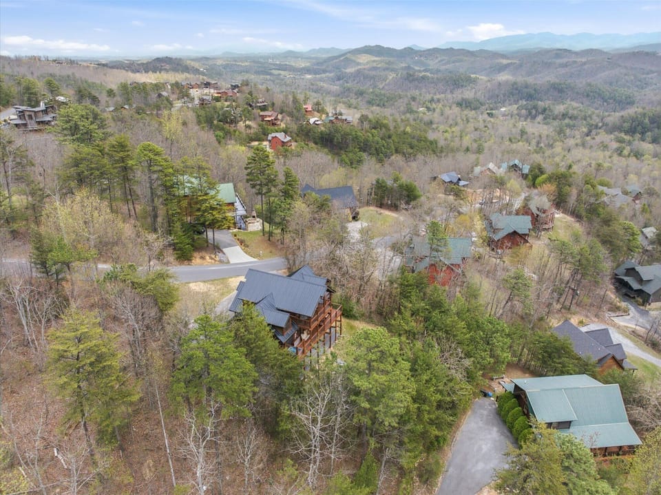 Aerial view of mountain retreat cabins nestled among forested hills with scenic Appalachian ridges extending to the horizon.