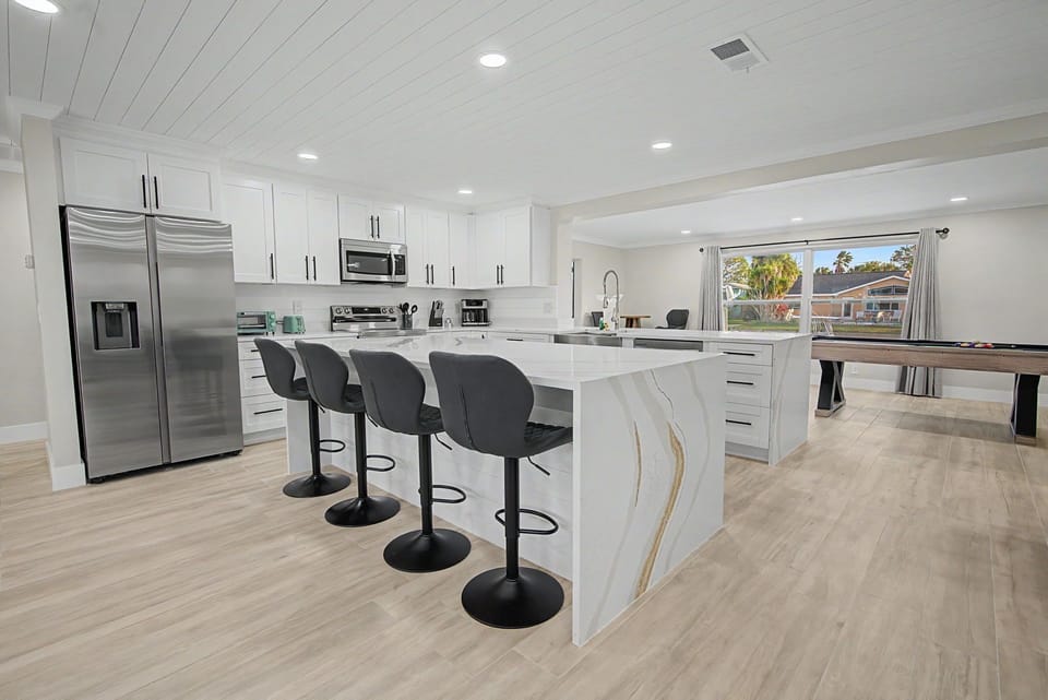 Your modern kitchen awaits with sleek white cabinets, stainless steel appliances, and a spacious island perfect for morning coffee or evening meals.
