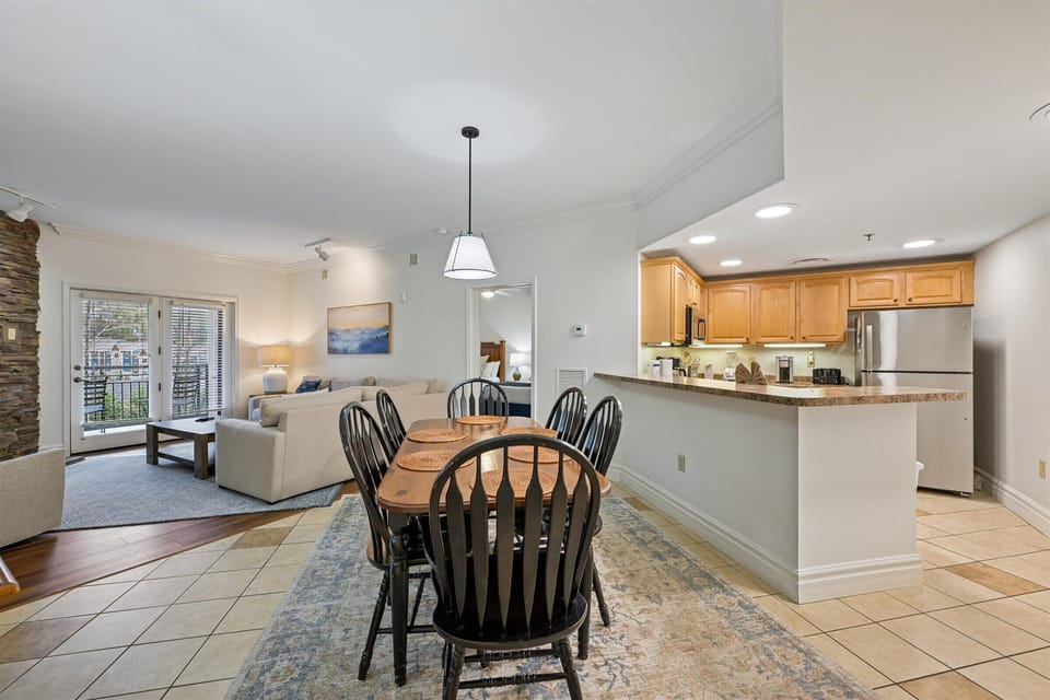 Your open-concept haven seamlessly blends kitchen, dining, and living spaces with warm wood cabinets and city balcony views.