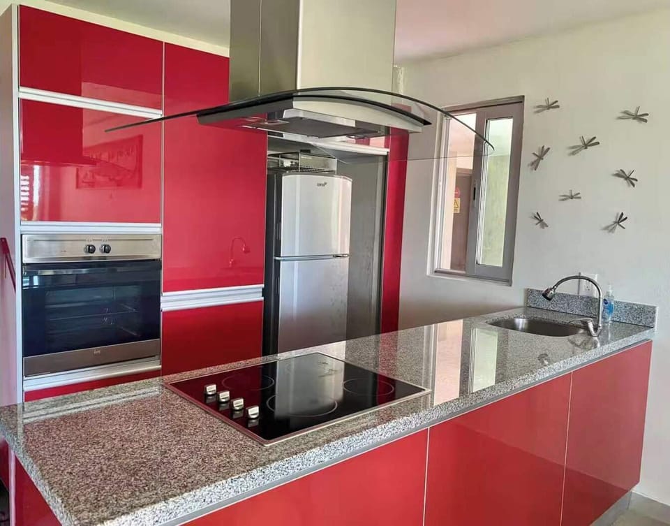 Modern kitchen w/ glossy red cabinets, island cooktop & stainless steel appliances