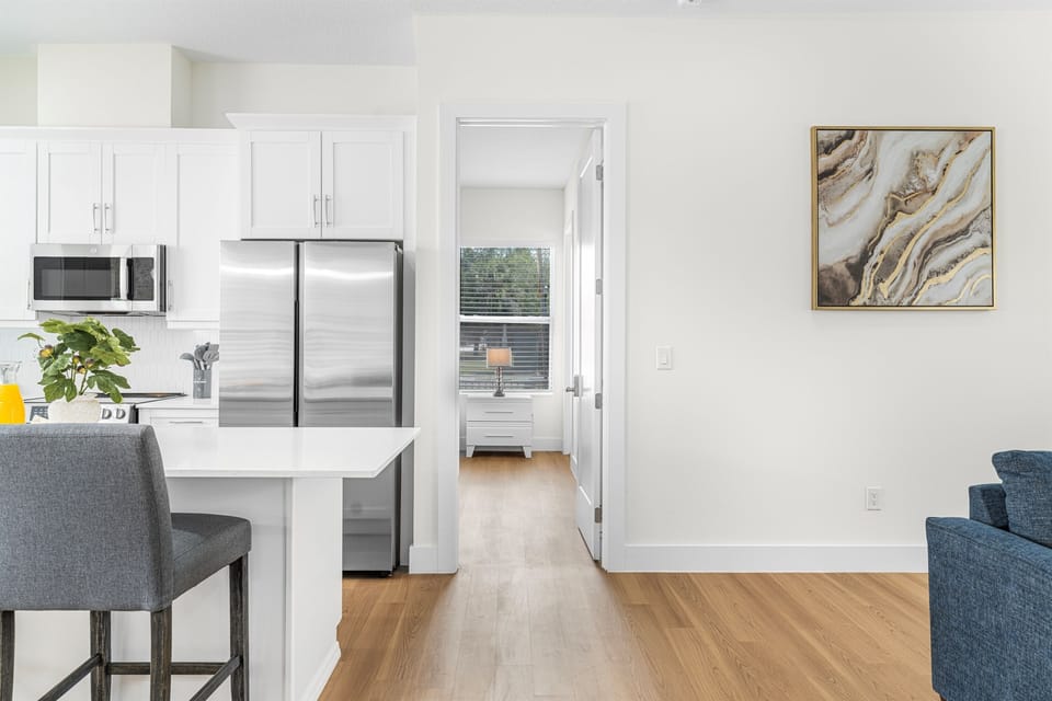 Bright, open-concept layout with a modern kitchen, stainless steel appliances, and a clear view into the bedroom—creating a spacious and airy feel throughout the home.