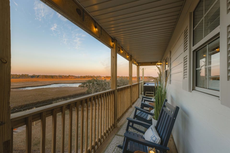 The covered back porch. A front row seat to coastal sunrises and marsh views. Perfect for slow mornings, quiet conversations, or unwinding after a beach day.