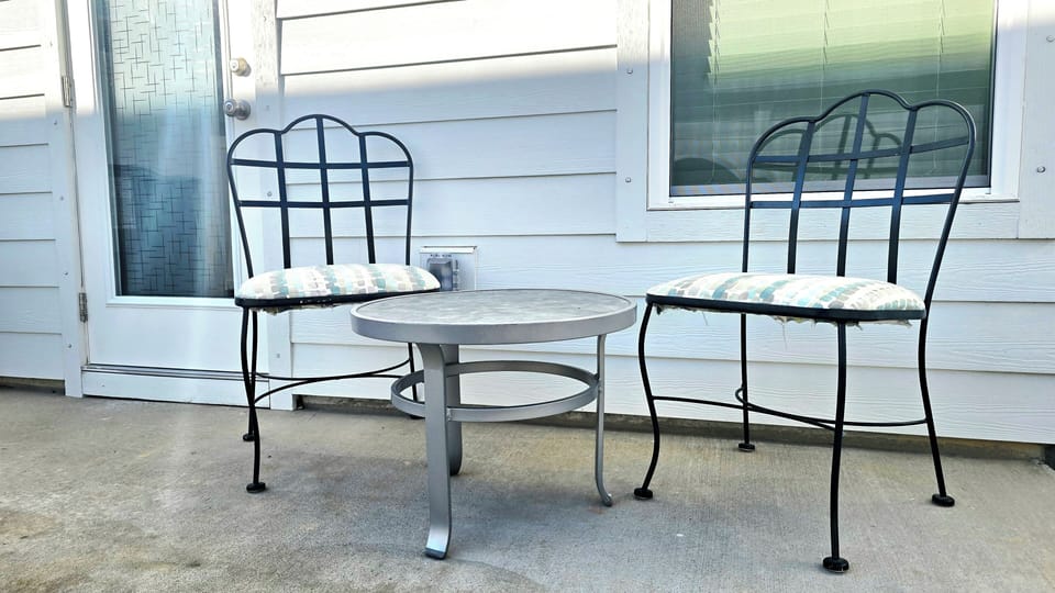 Step outside to a cozy back patio with two cushioned chairs and a round table.
