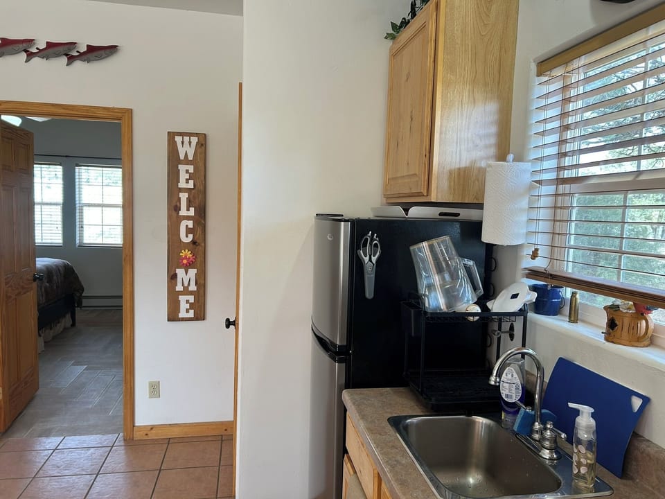 Highlighting the sink, fridge, and easy flow between kitchen & bedroom.