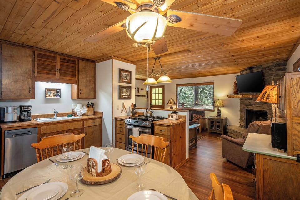 Step into your cozy cabin retreat with warm wood ceilings, a fully equipped kitchen, and a welcoming stone fireplace—your perfect home away from home awaits.