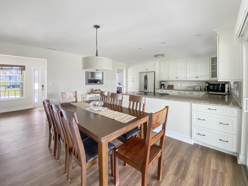 Spacious dining area with seating for eight, adjacent to a modern kitchen with granite countertops.
