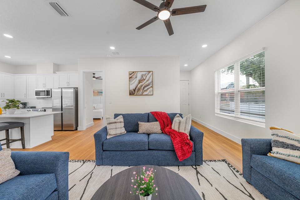 Bright living area with large windows and seamless flow into the fully equipped kitchen.