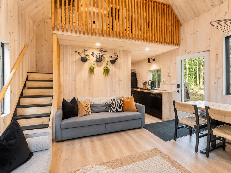 Open-concept living room with sofa bed, loft, and kitchen access."