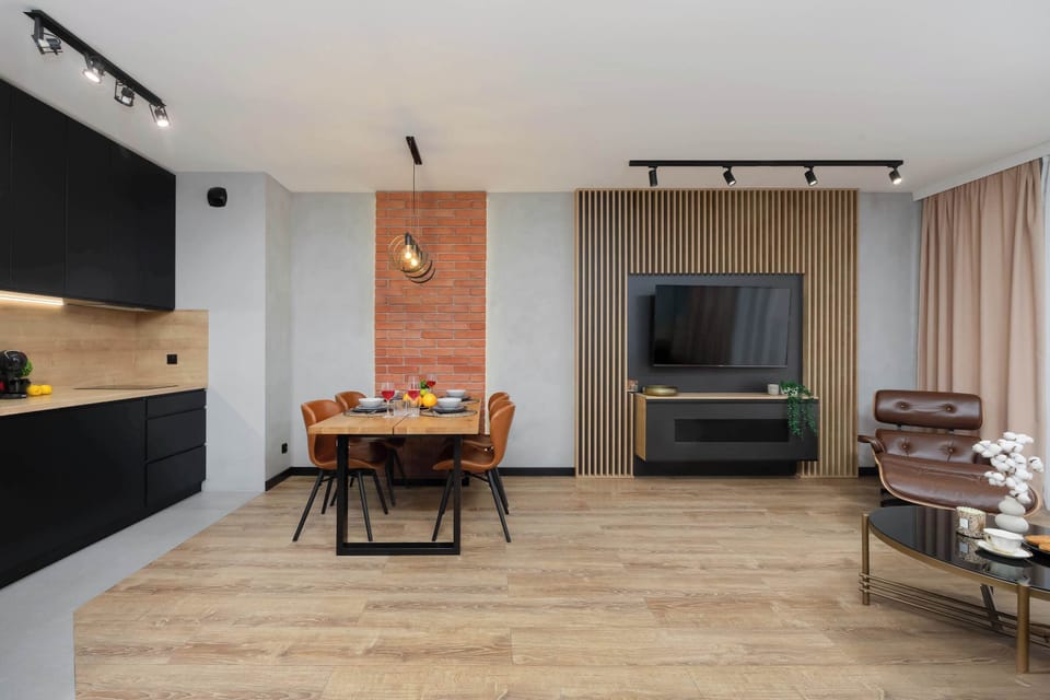 A spacious open-plan living area with a seating zone and a dining table placed centrally. The design combines clean lines with warm accents, creating a balanced and functional interior.