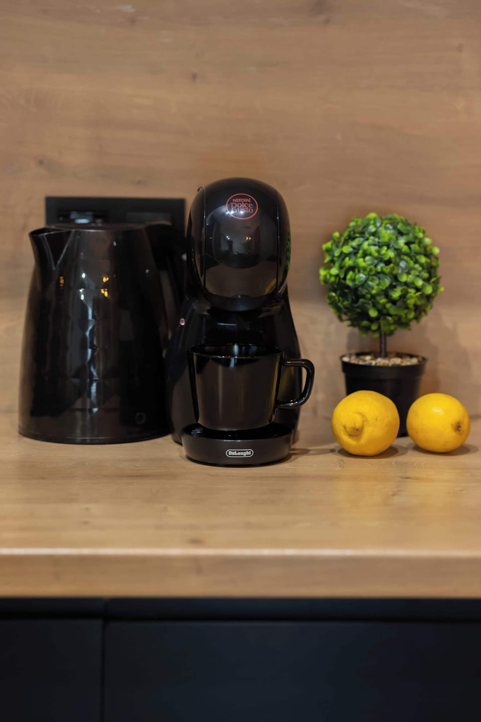 A kitchen countertop styled with small decorative elements and fresh lemons. The wooden surface and minimalist arrangement give a clean and cozy look.