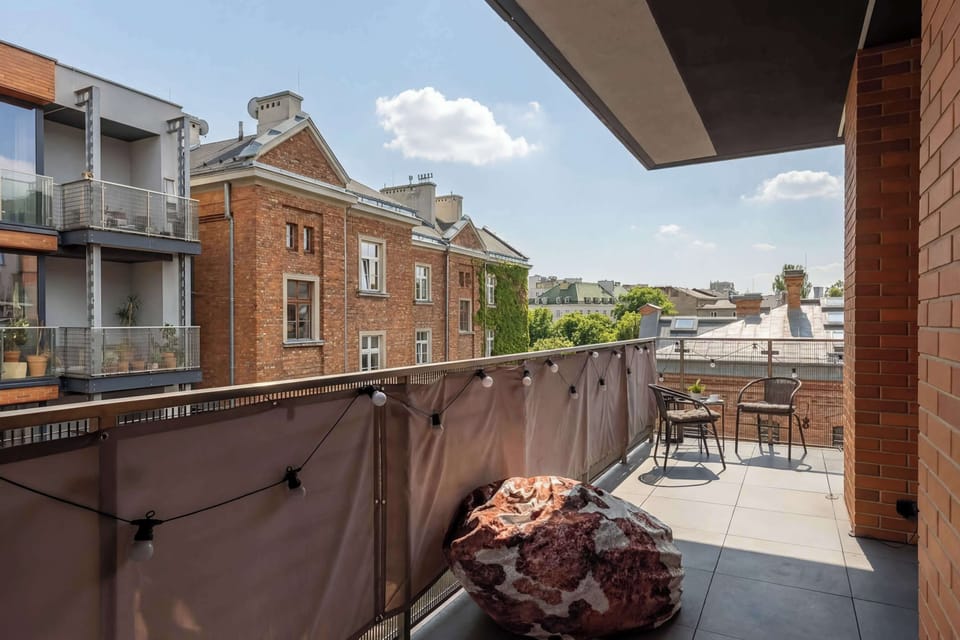 A view from the balcony of the surrounding urban landscape, showcasing the peaceful character of the neighborhood and railings covered with a safety mat.