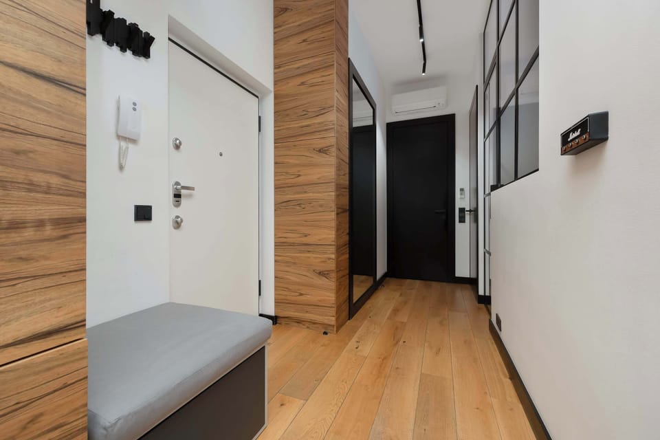 A modern entryway with a built-in closet, a large mirror, and a bench for putting on shoes.