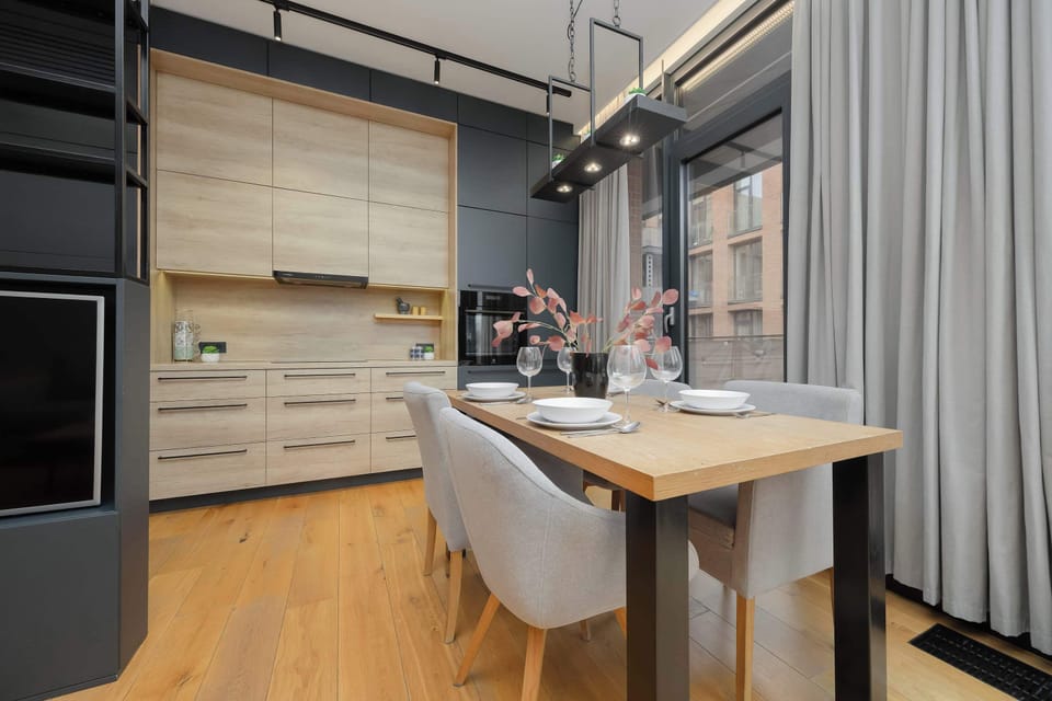A modern kitchenette with light wooden cabinet fronts and dark built-in elements, creating a harmonious whole.