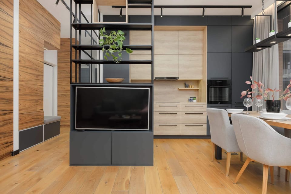 A stylish kitchenette with an island, above which modern lighting is suspended, combining cooking and dining functions.