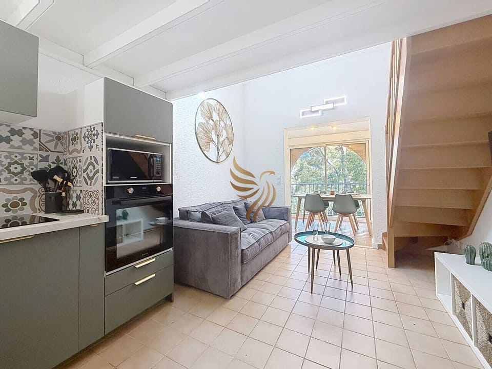 Pièce de vie lumineuse avec cuisine équipée, salon cosy et accès au duplex