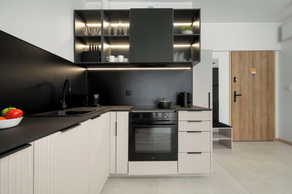 Kitchenette area with a combination of white cabinets and wooden accents near the entrance. The open layout connects seamlessly with the rest of the apartment, enhancing the sense of space.