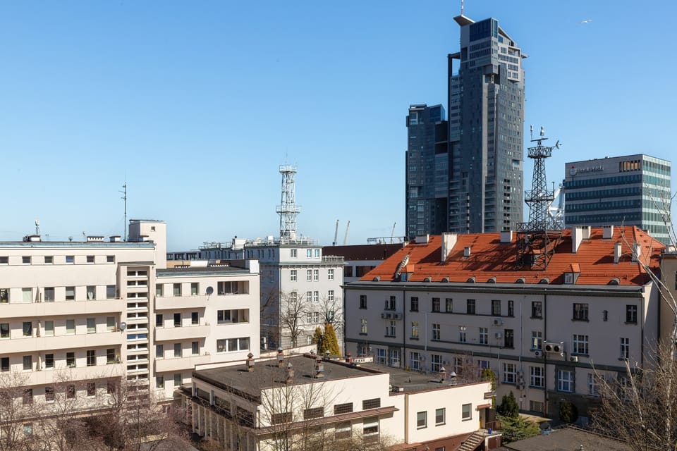 This panoramic city view highlights a mix of traditional red-roofed buildings and contemporary high-rise towers. The clear weather provides a sharp view of the city's architectural diversity.