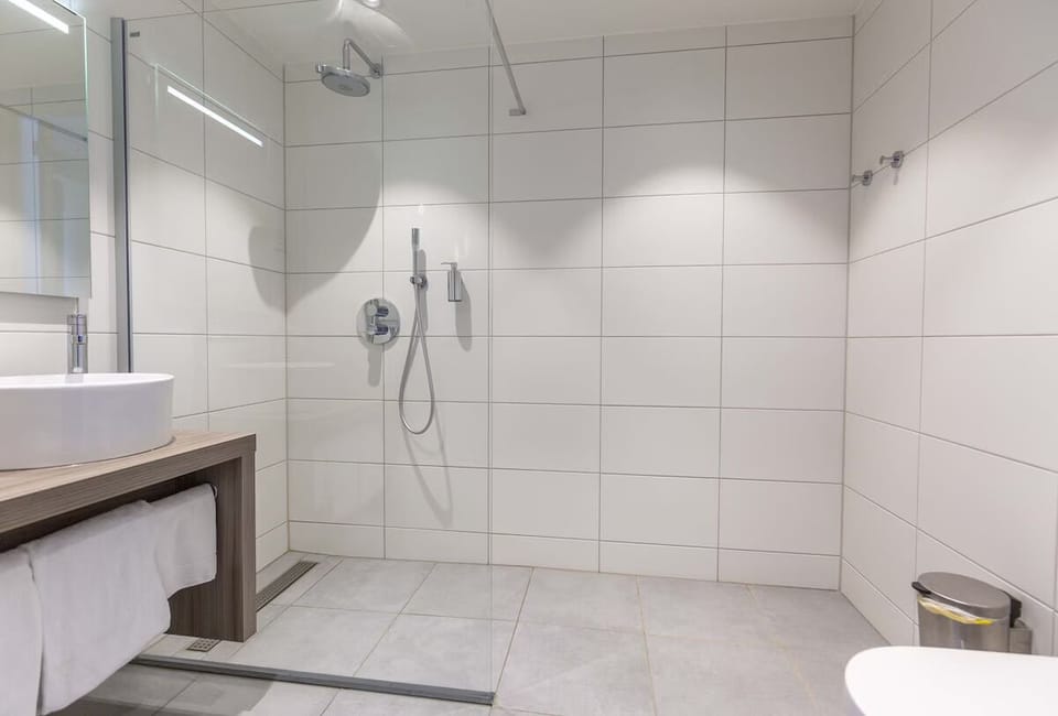 Refresh under a rainfall shower in a sleek, spotless space.