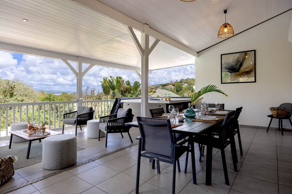 Large furnished terrace with lounge area and dining area. Enjoy the view of the tropical garden of Villa Émeraude.