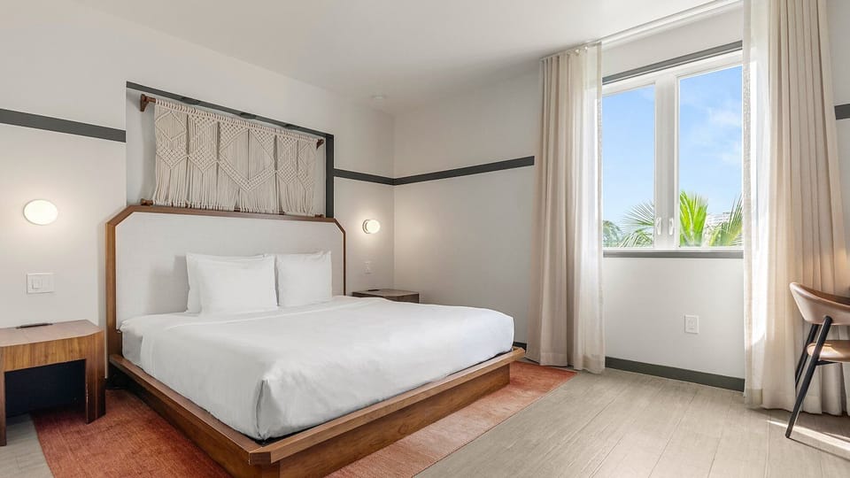 Unwind in crisp linens beside sunlit windows and calm tones.