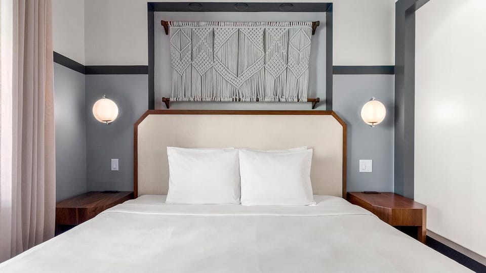 Drift off beneath statement wall art and soft bedside glow.