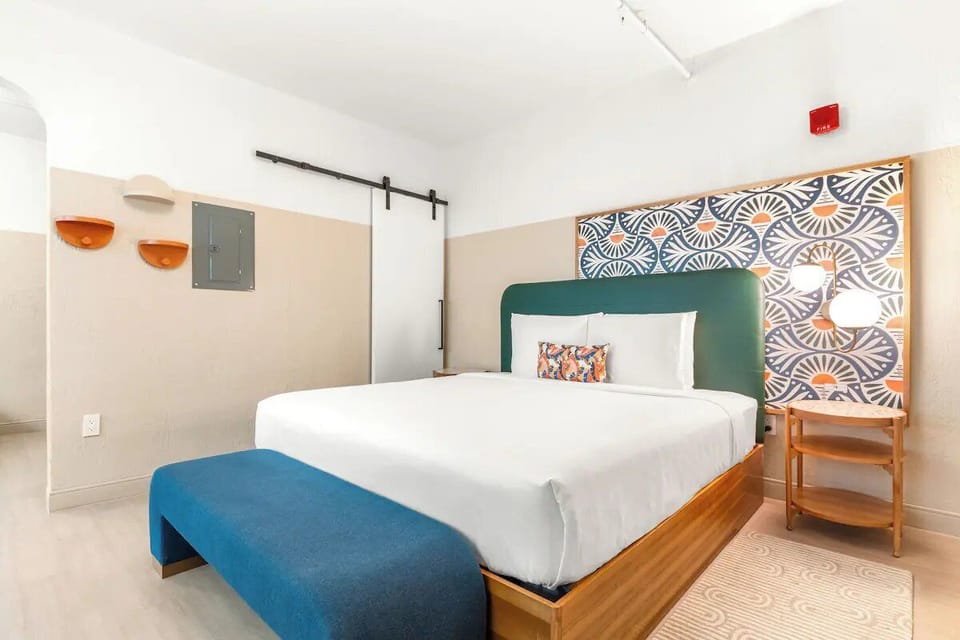 Sink into crisp linens beneath a bold, artful headboard.