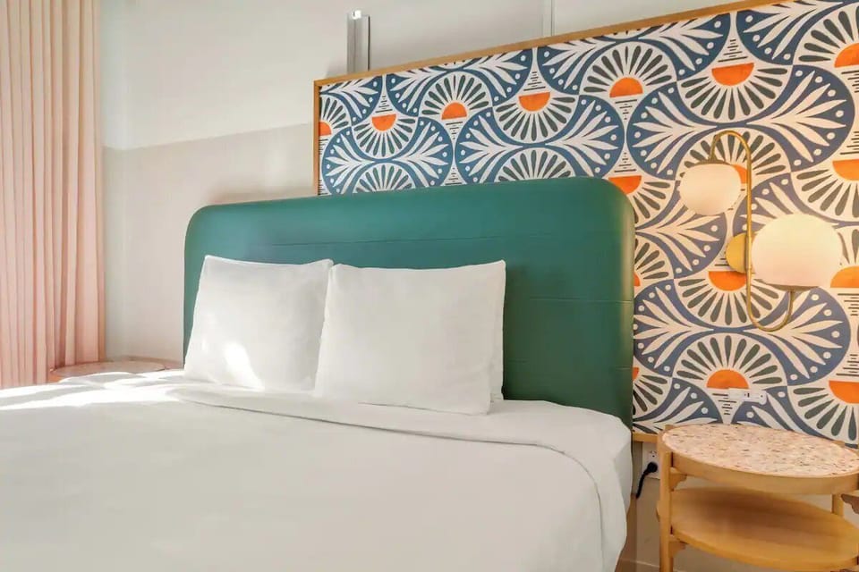 Sink into crisp linens beside a bold, artful headboard.